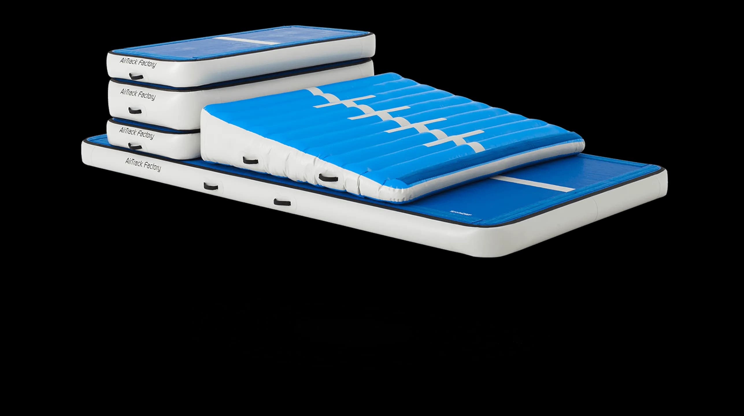 Stacked white-sided inflatable blue training mats with a blue wedge air ramp on top.